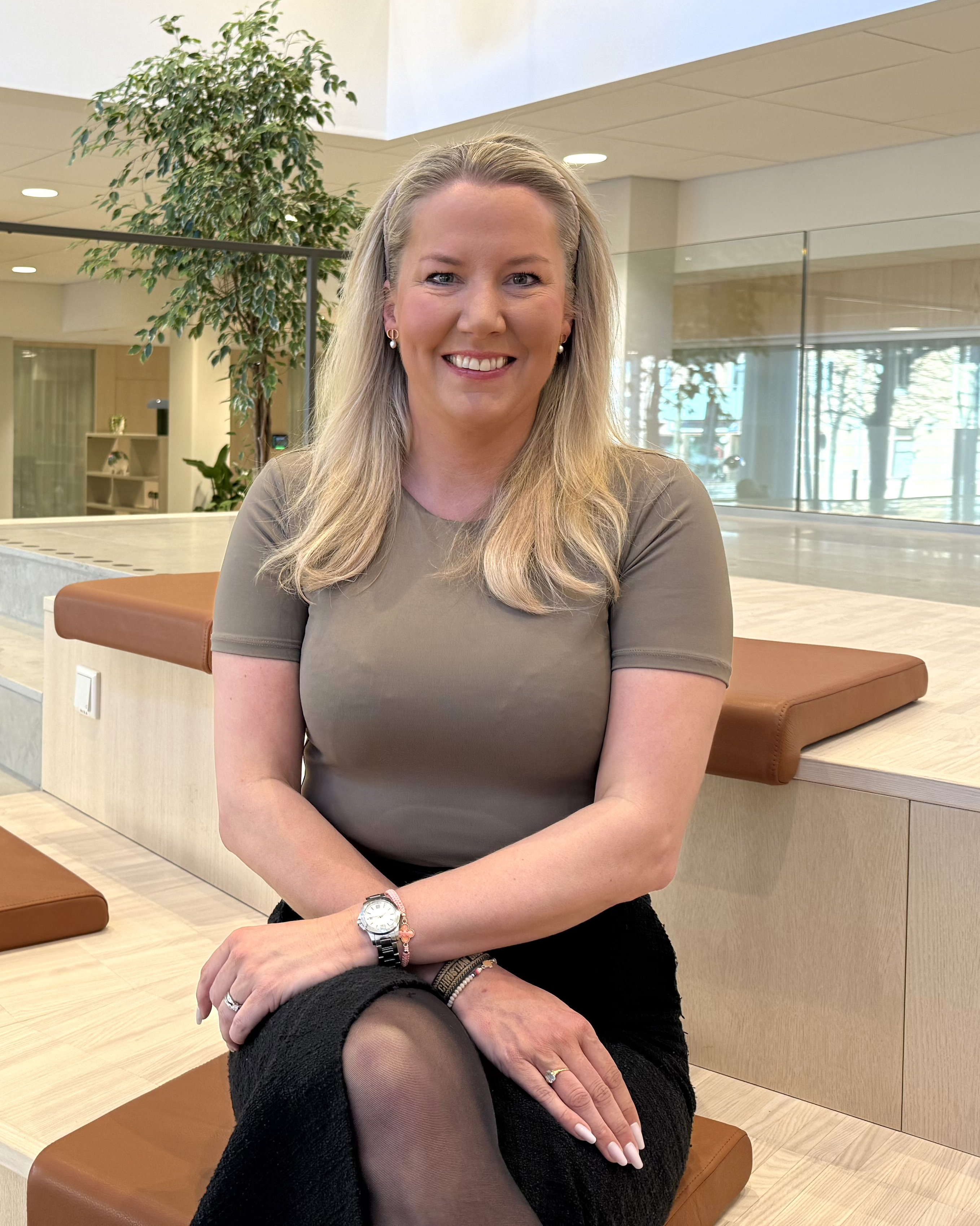 Kvinna sitter i en grandängtrappa, ler och tittar in i kameran