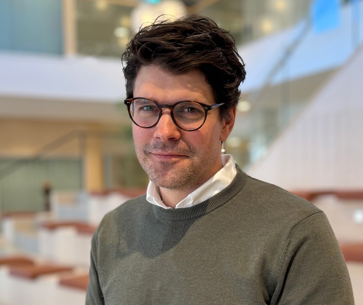 Man står vid ett ståbord, tittar in i kameran och ler