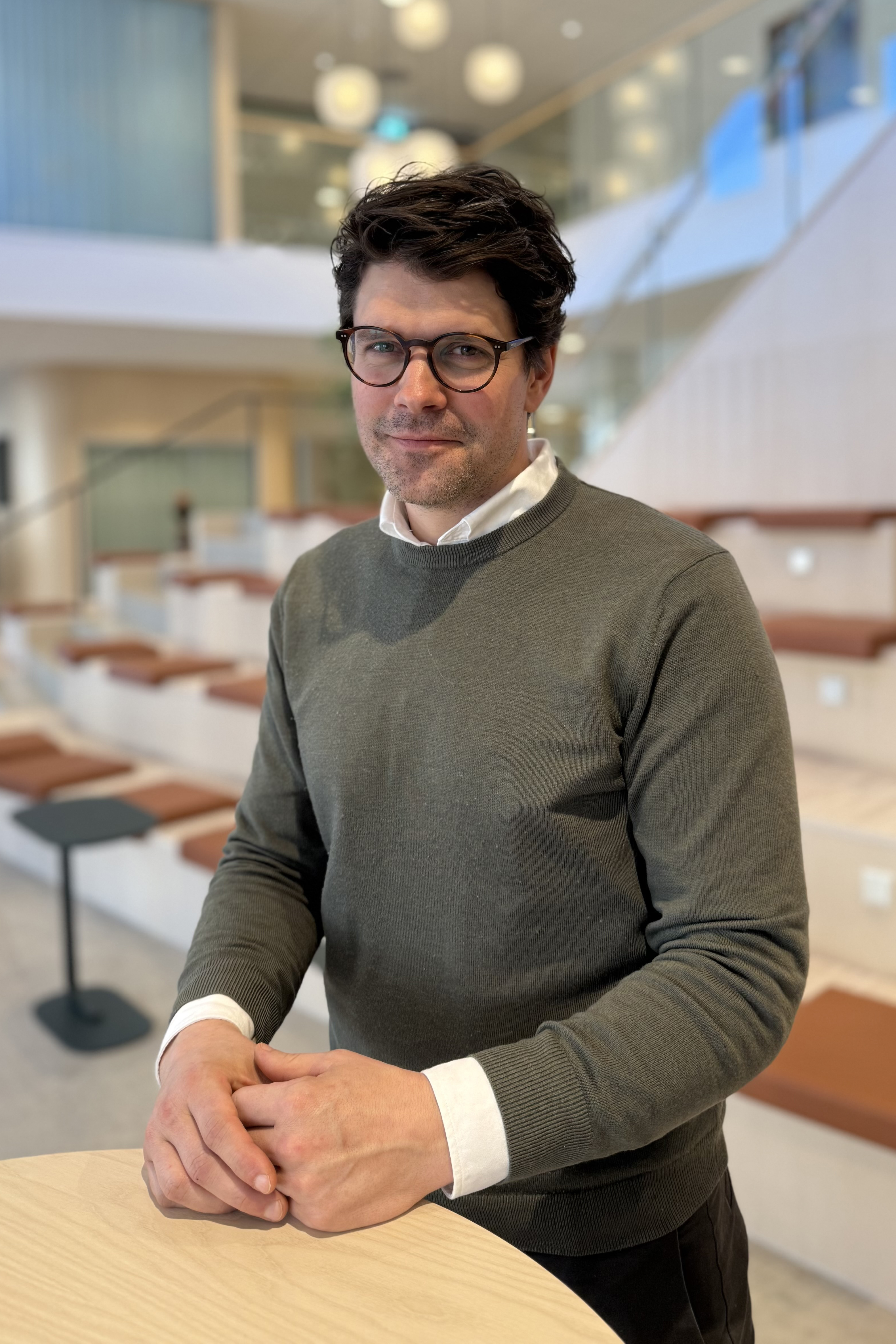 Man står vid ett ståbord, tittar in i kameran och ler