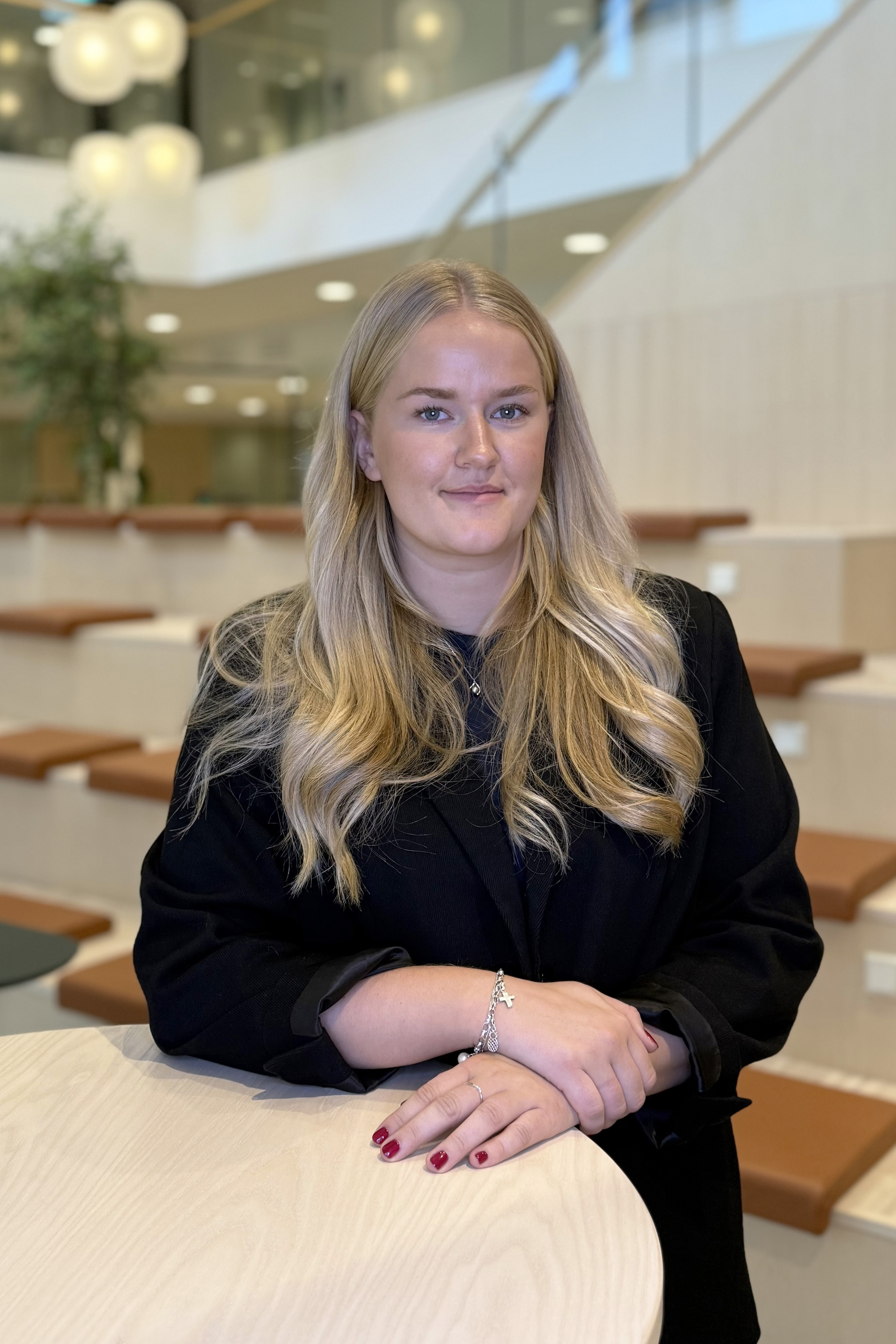 Kvinna står vid ett ståbord, ler och tittar in i kameran