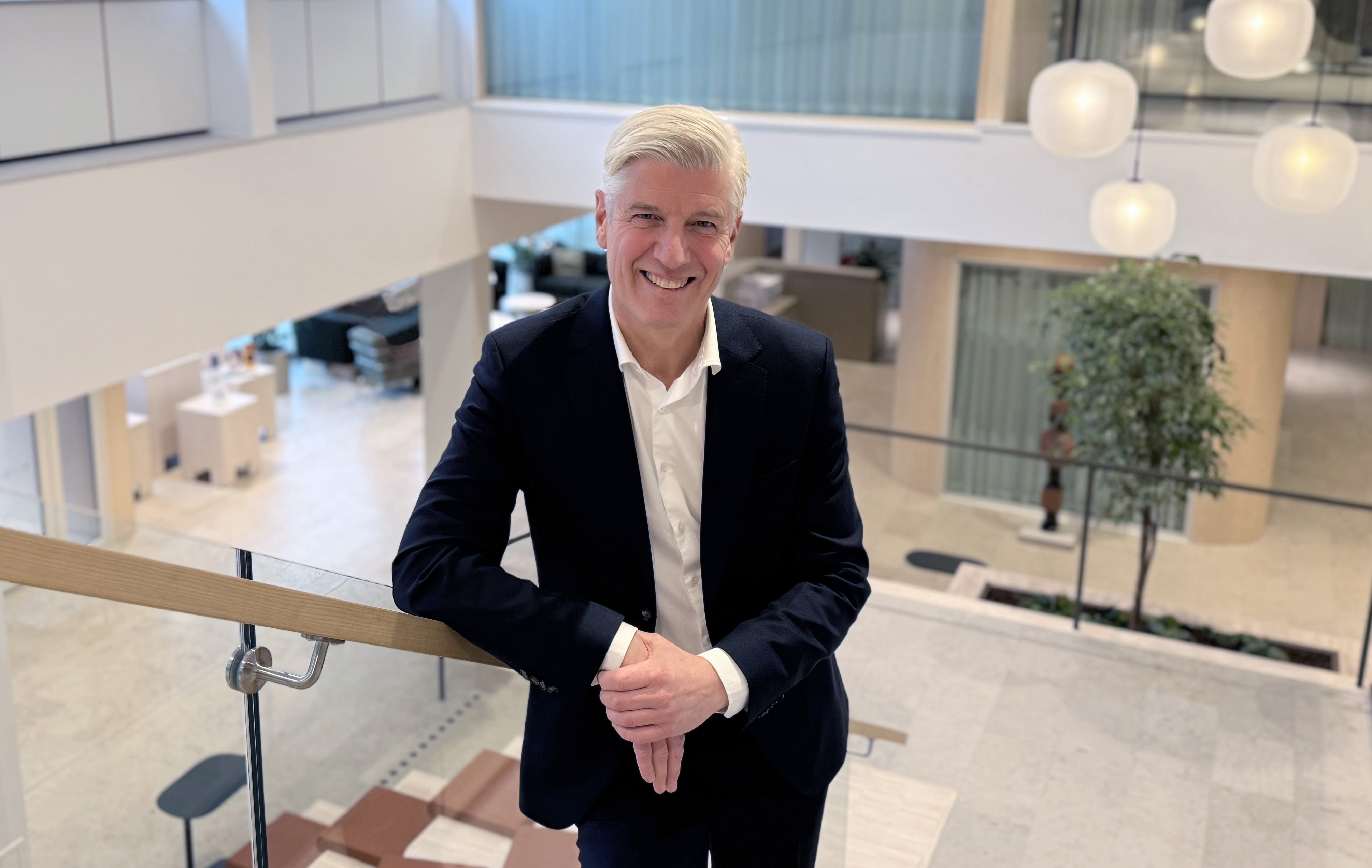 Man står högt upp i en gradängtrappa tittar upp in i kameran och ler