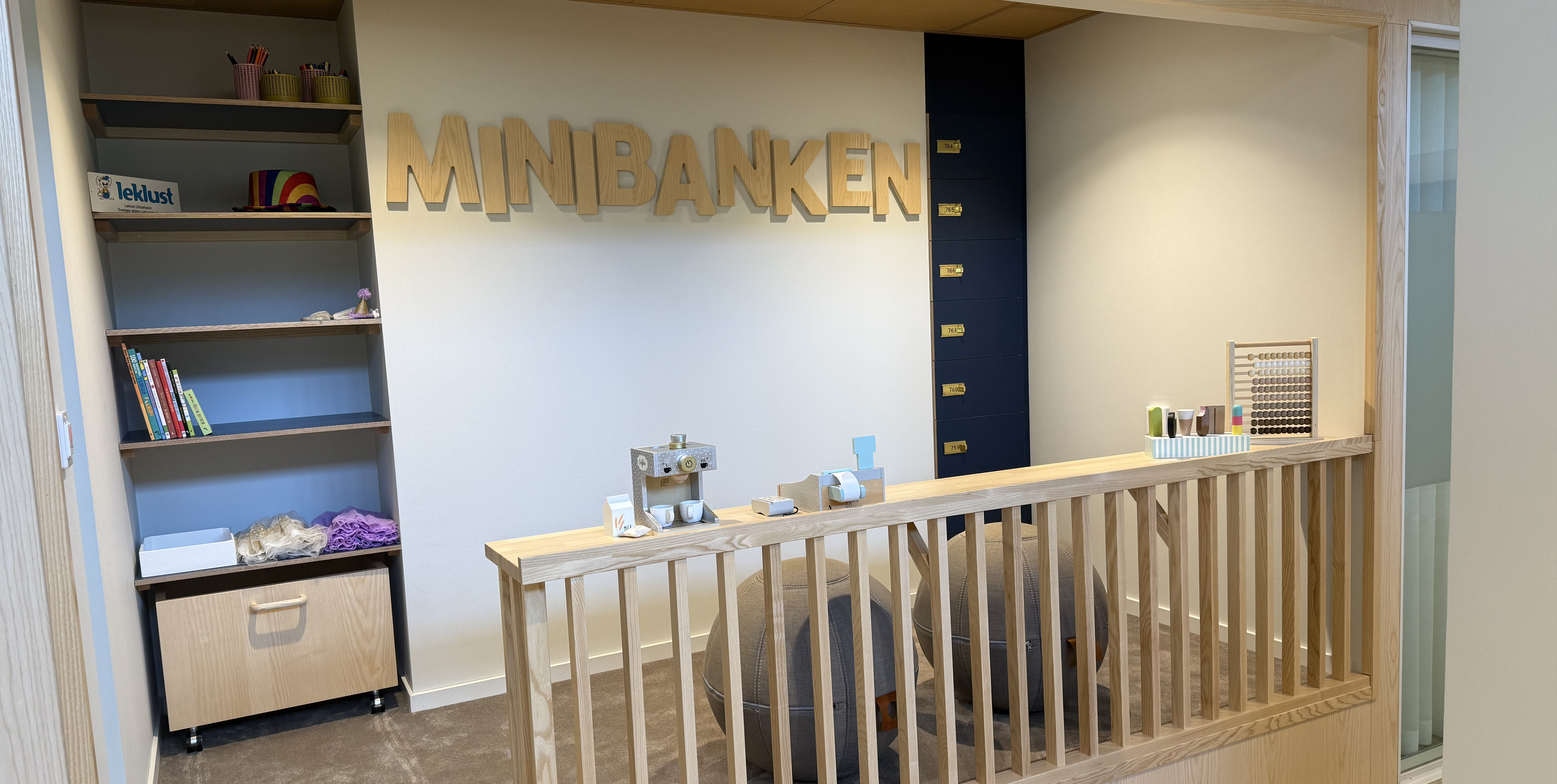 Ett upphöjt litet rum med träbokstäver - Minibanken- träleksaker och utklädningskläder