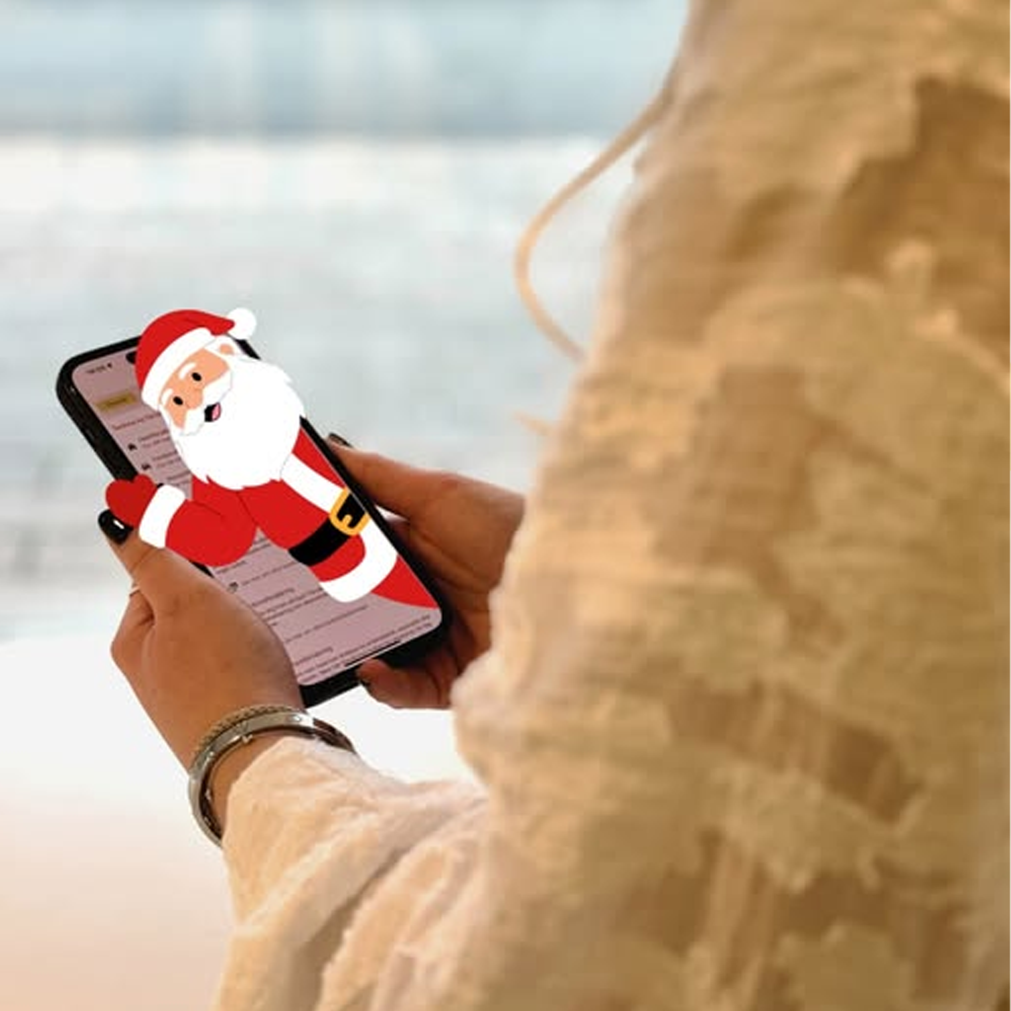 En person håller i en mobiltelefon, ur telefonen tittar en tomte ut