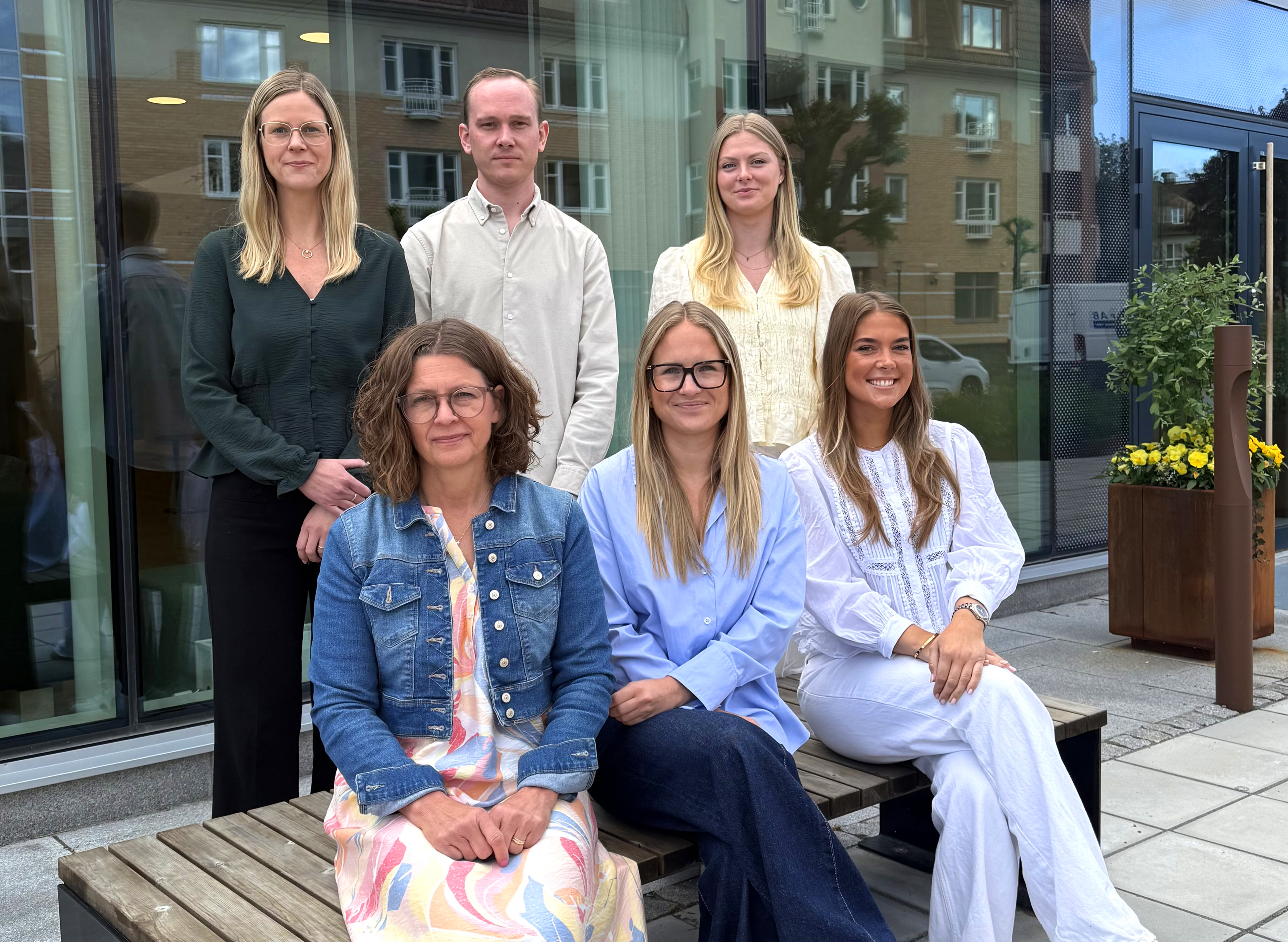 Kvinnor och män sitter och står utanför en bankbyggnad