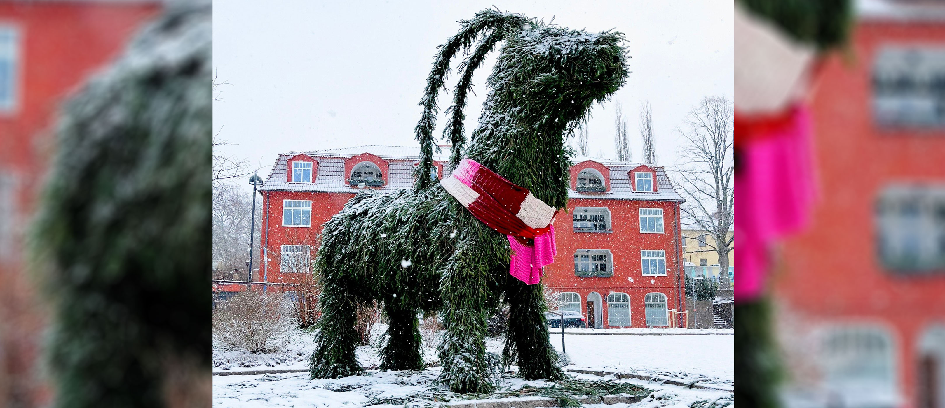 Julbock klädd i gran med en halsduk, står i snö