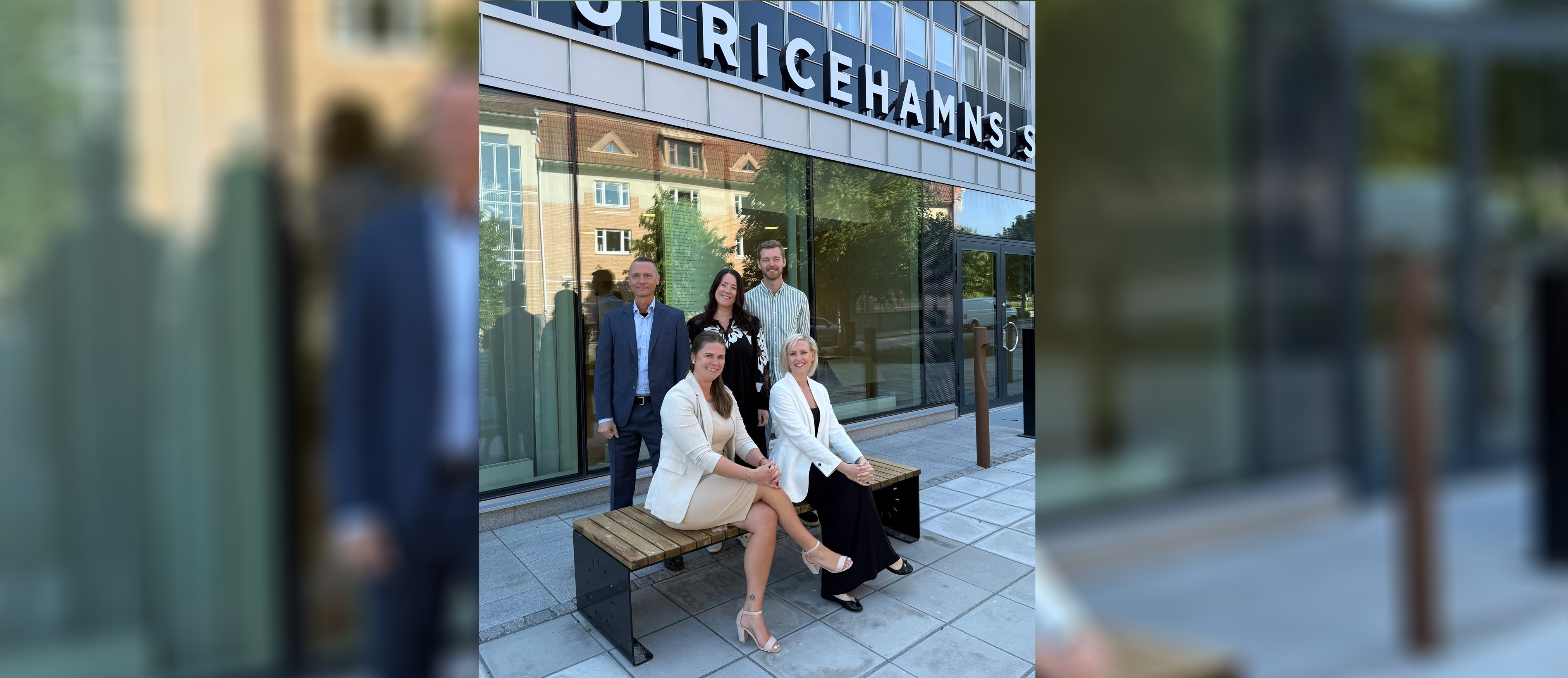 Tre kvinnor och två män sitter och står framför en bankentré där det står Ulricehamns Sparbank på en skylt