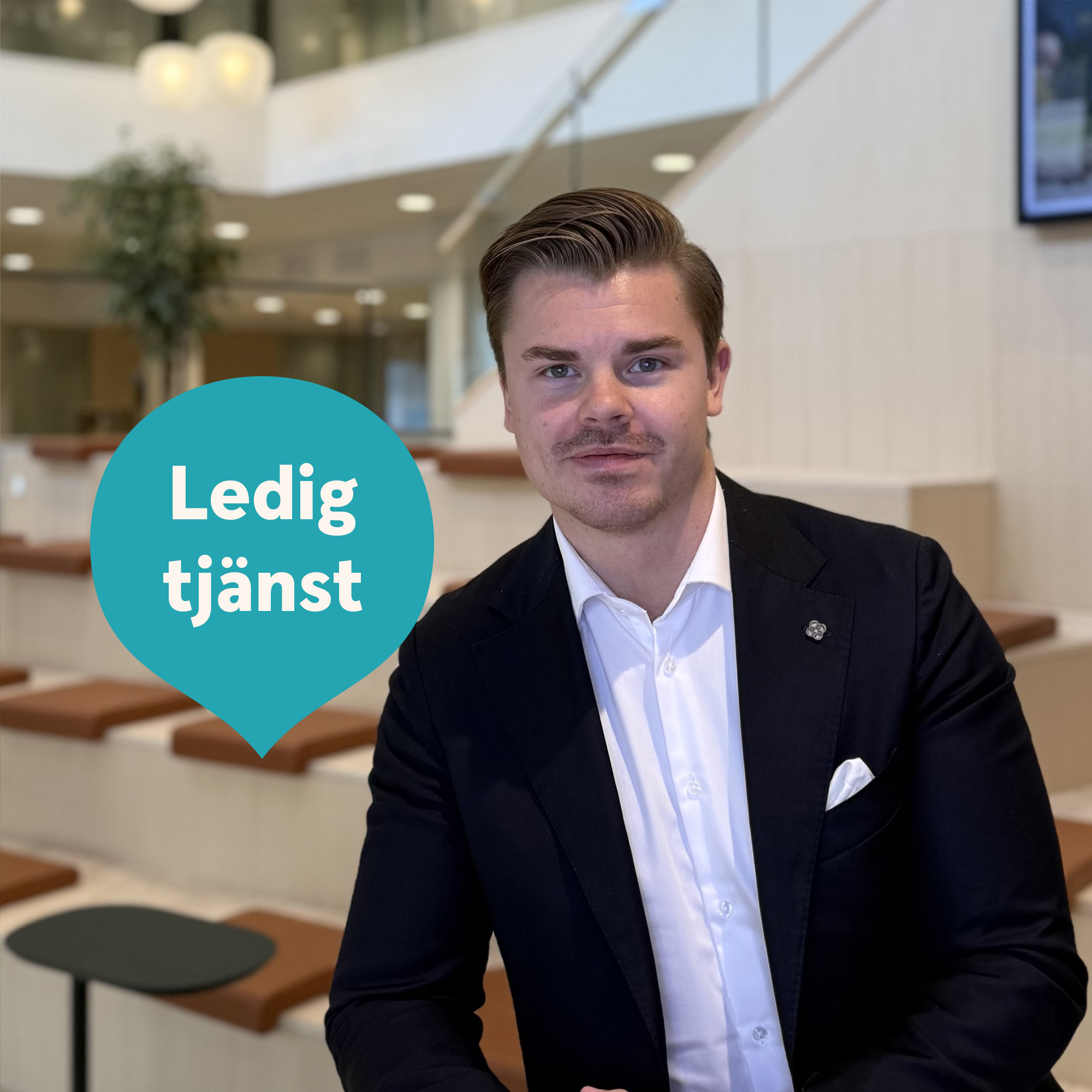 Man lutar sig mot ett ståbord, tittar in i kameran och ler